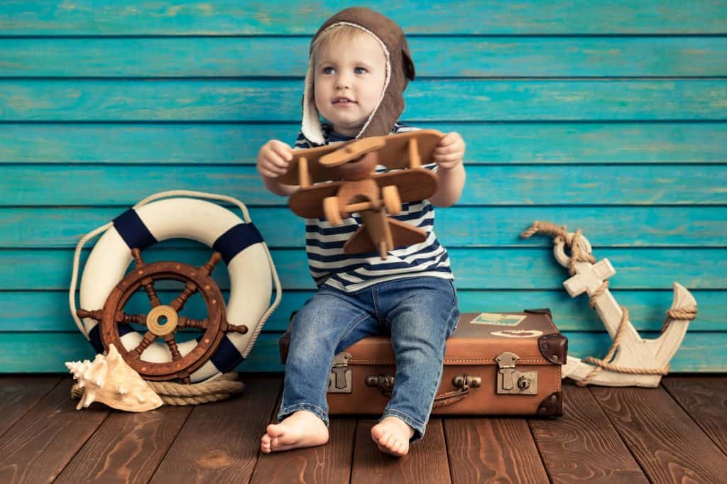 Bambino felice che gioca con un aeroplanino giocattolo