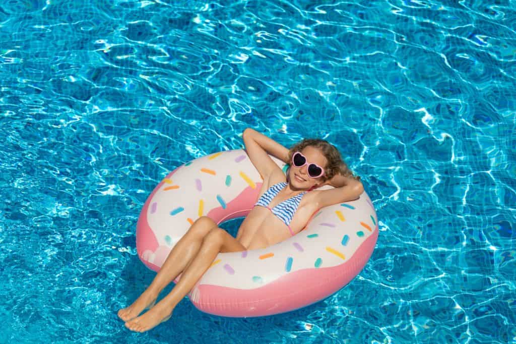 Bambino felice che nuota nella piscina all'aperto
