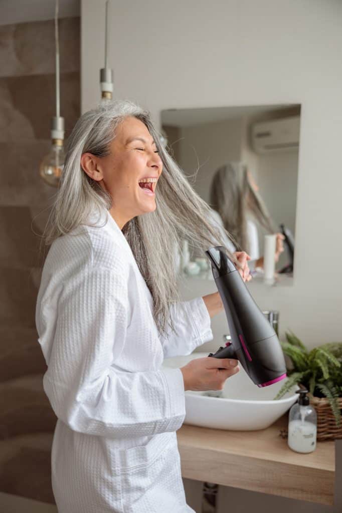 Donna felice che si sistema i capelli dopo aver fatto il bagno